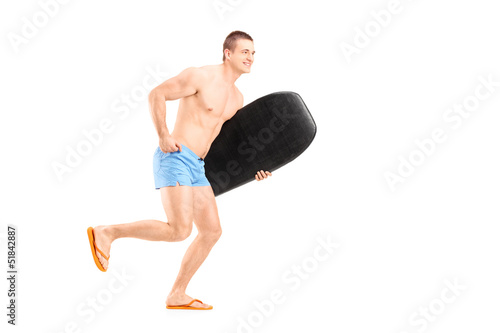 Photo: Full length portrait of a male surfer holding a surfboard and ru Full length portrait of a male surfer holding a surfboard and ru