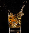 Whiskey splashing out of glass on black background