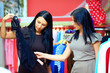 two happy women shopping in clothes store