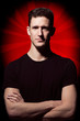 Man in black t-shirt posing on gray background.