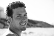 Handsome young man with a goatee smiling on the beach