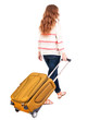 back view of walking  woman  with suitcase
