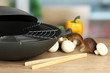 Black wok pan and vegetables on kitchen table, close up