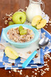 Useful oatmeal in bowl with fruit on wooden table close-up