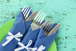 Forks and knives wrapped in blue paper napkins,