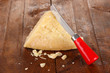 Piece of Parmesan cheese with knife on wooden table close-up
