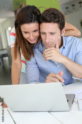 Photo: Couple at home sitting in front of laptop Couple at home sitting in front of laptop