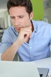 Foto: Man with doubtful look in front of laptop Man with doubtful look in front of laptop