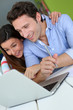 Foto: Couple at home sitting in front of laptop Couple at home sitting in front of laptop