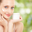 Cute woman applying cream to her face