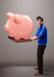 Handsome man holding a huge savings piggy bank