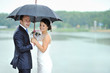 Happy bride and groom in a rainy wedding day hiding from rain