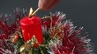 person lighting the candle on holiday ornament