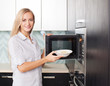 Woman warms up food in the microwave
