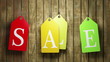 Colorful sale tags hanging on wooden background. Seamless loop.