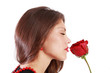 Beautiful woman sniffs red rose with closed eyes