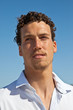 Handsome mediterranean young man with curly hair on the beach