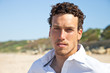 Handsome mediterranean young man with curly hair on the beach