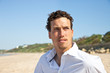 Handsome mediterranean young man with curly hair on the beach