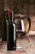 Photo: Wine bottles with barrel on wooden background Wine bottles with barrel on wooden background