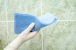 female hand cleaning kitchen tiles with sponge