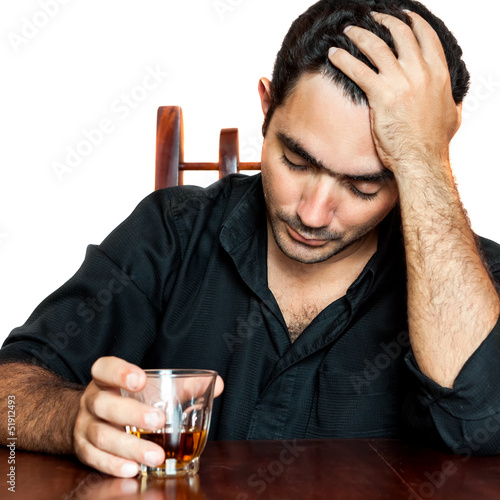 Photo: Hispanic man holding an alcoholic drink and suffering a headache Hispanic man holding an alcoholic drink and suffering a headache