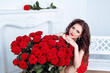 Beautiful brunette woman with red roses flowers bouquet in moder