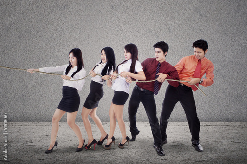 Photo: Business team pulling chain on grey Business team pulling chain on grey
