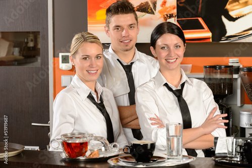 Photo: Three server posing in uniform in cafe Three server posing in uniform in cafe