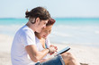 Photo: Young Couple at Seaside with Digital Tablet Young Couple at Seaside with Digital Tablet
