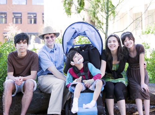 Photo: Father sitting with his biracial children and disabled son Father sitting with his biracial children and disabled son