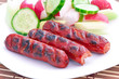 grilled sausages on the grill and a salad of fresh vegetables