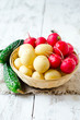Fresh young potatoes , cucumbers and radishes in a basket
