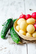 .Fresh young potatoes , cucumbers and radishes in a basket