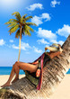Foto: Woman in sarong on a coconut tree Woman in sarong on a coconut tree