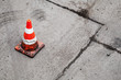 Photo: Red and white striped warning cone on dirty asphalt Red and white striped warning cone on dirty asphalt