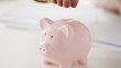 female hand inserting euro money into piggy bank