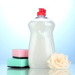 Dishwashing liquid with sponges and flower on blue background