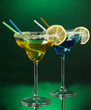Yellow and blue cocktails in glasses on color background