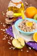 Useful oatmeal in bowl with fruit on wooden table close-up