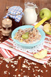 Useful oatmeal in bowl with fruit on wooden table close-up