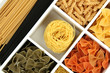 Different types of pasta in white wooden box sections close-up