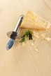 Piece of Parmesan cheese with knife on wooden table close-up