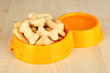 Dry dog food in bowl on wooden background