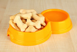 Dry dog food in bowl on wooden background