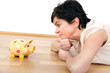 Woman looks thoughtfully at the piggy bank