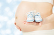 Pregnant woman belly with newborn baby booties