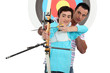 Foto: Man and a teenager practicing archery Man and a teenager practicing archery