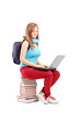 Photo: A smiling student with backpack typing on a laptop and sitting o A smiling student with backpack typing on a laptop and sitting o