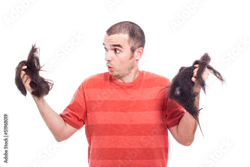 Photo: Surprised bald man holding his shaved hair Surprised bald man holding his shaved hair